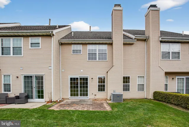 a view of a white house next to a yard with big trees