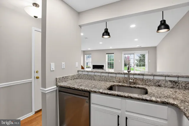 a large kitchen with stainless steel appliances granite countertop a refrigerator a oven and white cabinets with wooden floor