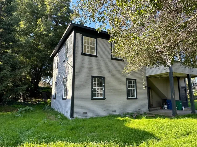 a front view of house with yard and trees in the background