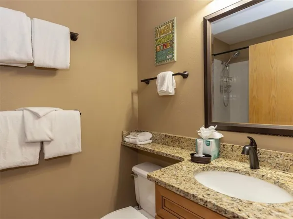 a bathroom with a granite countertop sink a mirror and a toilet