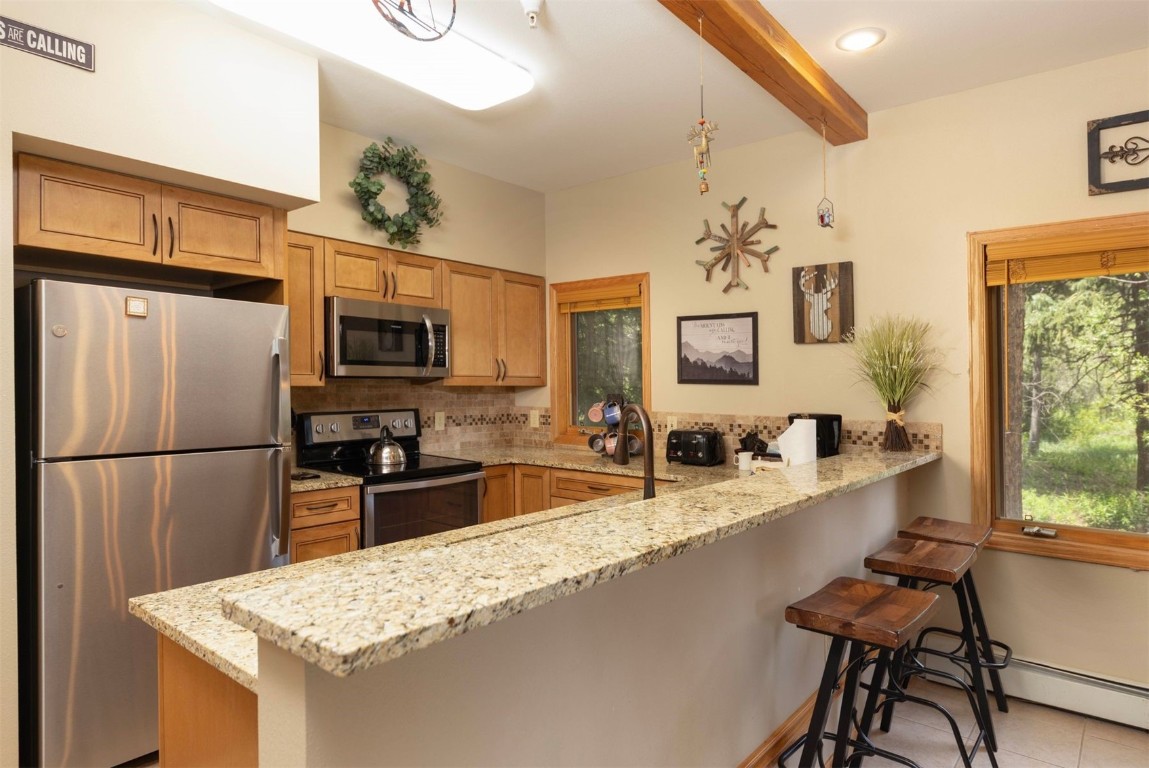 600 4 O Clock Road, Unit A11 Breckenridge, CO 80424 - Photo 9 of 22 a kitchen with stainless steel appliances granite countertop a refrigerator and a stove top oven