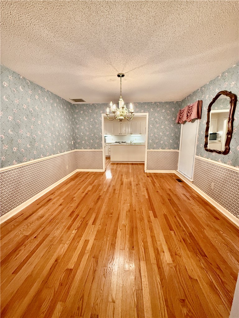 235 Stonehaven Way Seneca, SC 29672 - Photo 22 of 35 A classic chandelier illuminates the spacious dining room, boasting gleaming hardwood floors and an inviting kitchen view.