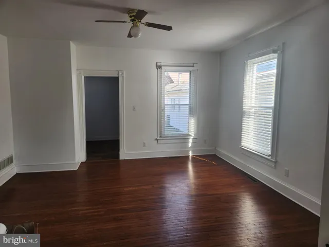 an empty room with wooden floor closet and windows