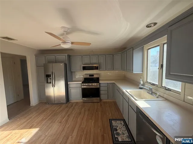 a large kitchen with stainless steel appliances granite countertop a sink dishwasher a refrigerator and wooden floor