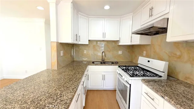 a kitchen with granite countertop white cabinets and a sink