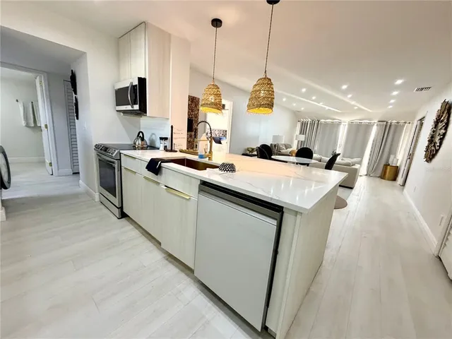 a kitchen with stainless steel appliances granite countertop a sink a stove and a wooden floors