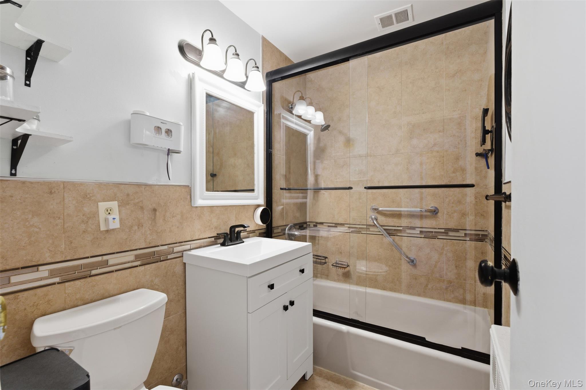 25 Trinity Place, Unit 2K New Rochelle, NY 10805 - Photo 13 of 25 The bathroom features a tiled shower with a sliding glass door, a white vanity, and a toilet