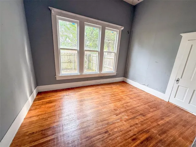 a view of an empty room with wooden floor and a window