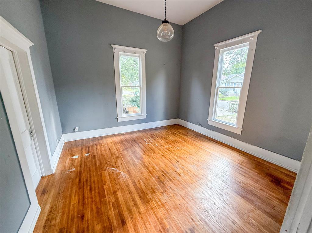 1210 Monroe Street Commerce, TX 75428 - Photo 13 of 20 an empty room with wooden floor and windows