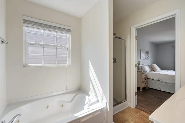 a bathroom with a tub shower and bedroom view