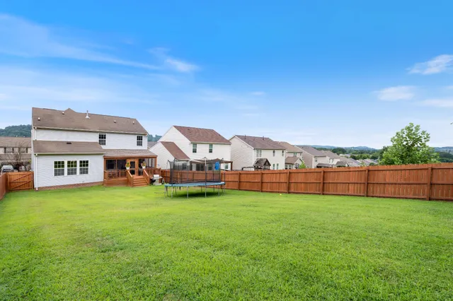 a view of a house with a big yard and large trees