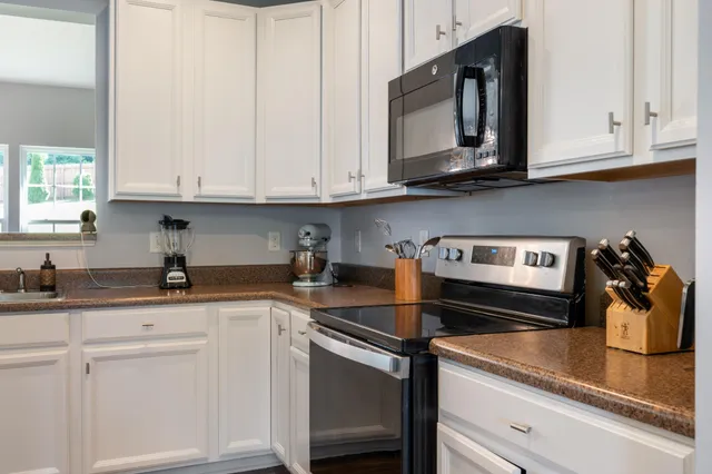 a kitchen with granite countertop white cabinets and white appliances