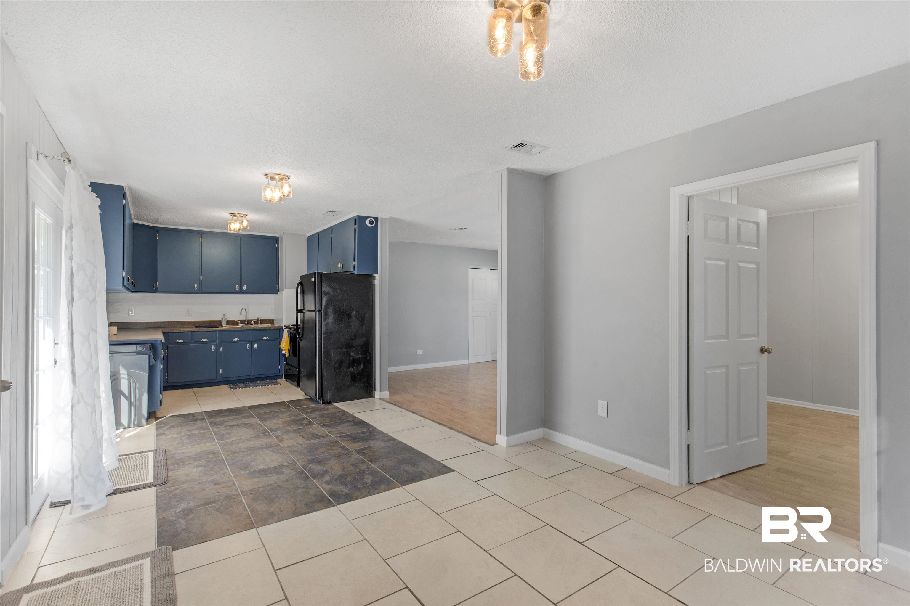 501 West Craig Street Atmore, AL 36502 - Photo 9 of 26 Kitchen with hardwood / wood-style flooring, blue cabinets, and black refrigerator