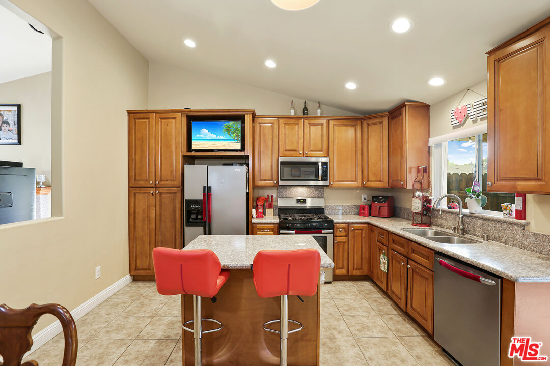 9225 Flax Place Riverside, CA 92503 - Photo 11 of 35 a kitchen with stainless steel appliances granite countertop a stove a sink dishwasher a dining table and chairs with wooden floor