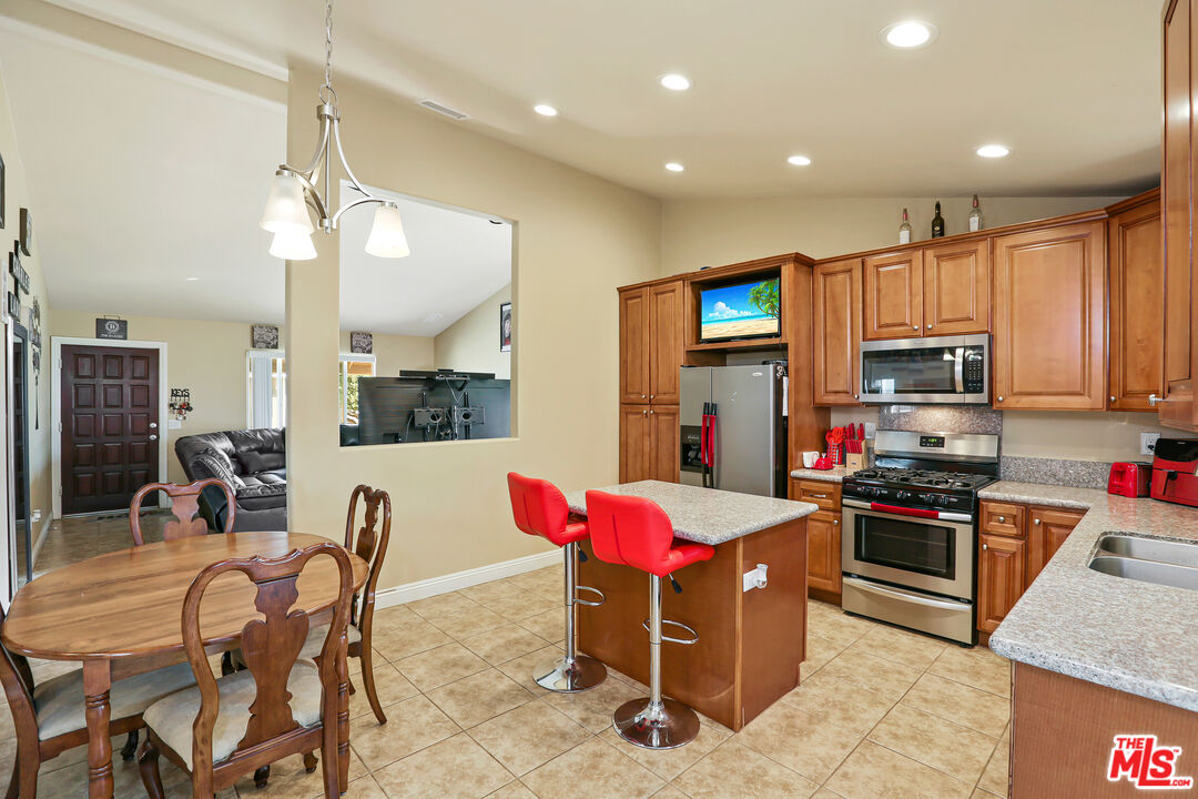 9225 Flax Place Riverside, CA 92503 - Photo 12 of 35 a kitchen with stainless steel appliances kitchen island granite countertop a refrigerator a stove top oven a sink dishwasher and white cabinets with wooden floor