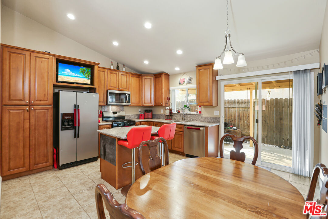 9225 Flax Place Riverside, CA 92503 - Photo 8 of 35 a kitchen with stainless steel appliances granite countertop a refrigerator a sink dishwasher a stove and a dining table with wooden floor