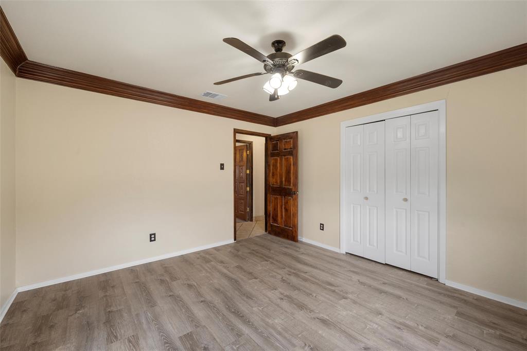 3433 West Tours Road West, TX 76691 - Photo 30 of 40 Unfurnished bedroom featuring ornamental molding, light wood finished floors, ceiling fan, and a closet