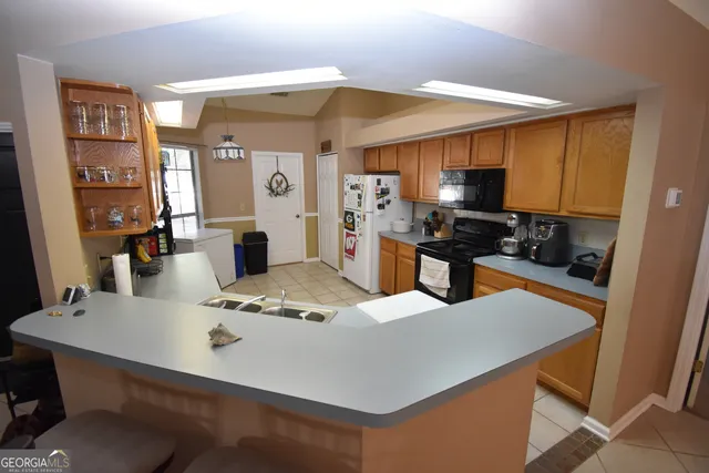 a kitchen with stainless steel appliances granite countertop a sink a stove a refrigerator a dining table and chairs with wooden floor