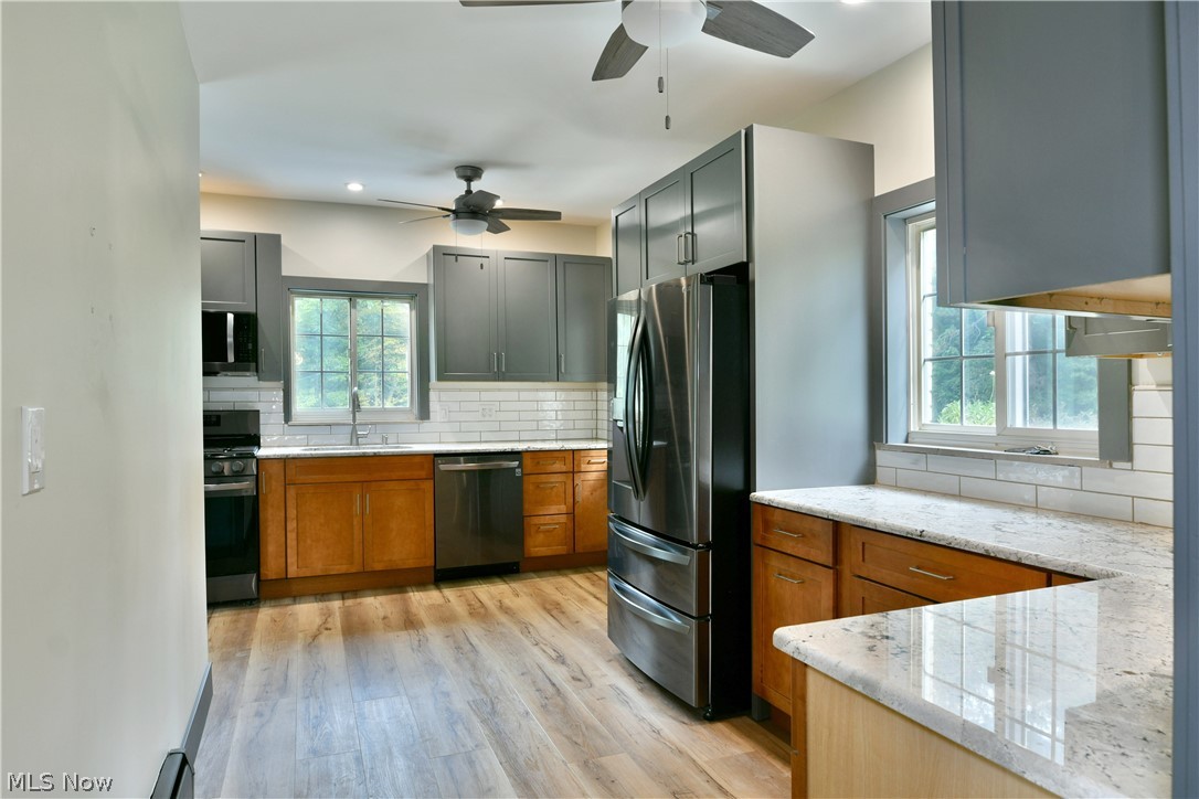 892 Yankee Run Road Masury, OH 44438 - Photo 15 of 50 Modern kitchen with wood-finish flooring, two-tone cabinetry, stainless steel appliances, and light-colored countertops