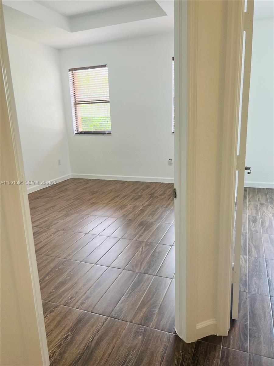 11219 Southwest 234 Terrace, Unit 11219 Homestead, FL 33032 - Photo 11 of 16 an empty room with wooden floor and windows