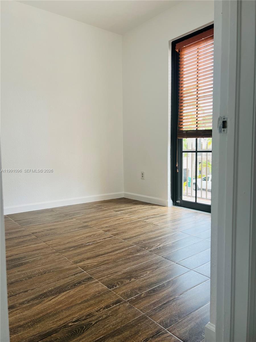 11219 Southwest 234 Terrace, Unit 11219 Homestead, FL 33032 - Photo 13 of 16 a view of an empty room with wooden floor and a window