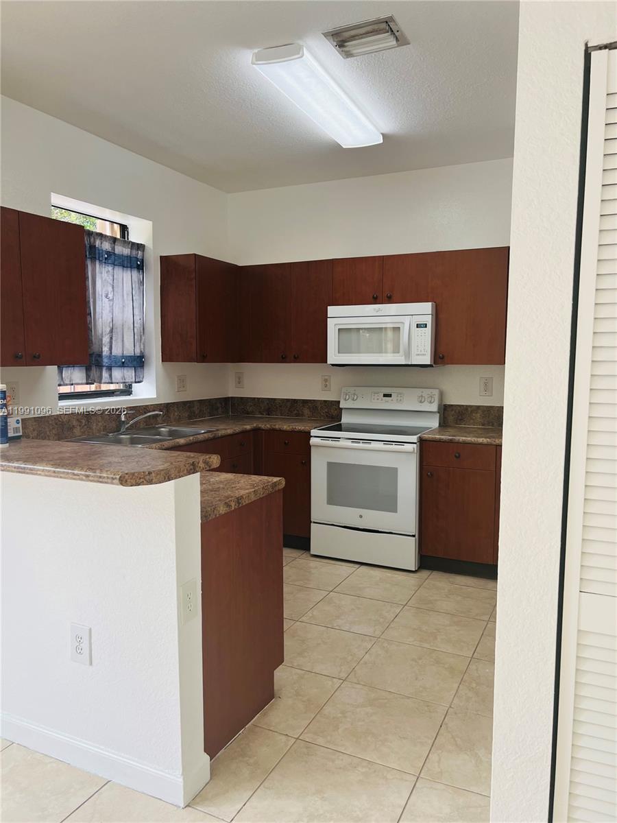 11219 Southwest 234 Terrace, Unit 11219 Homestead, FL 33032 - Photo 7 of 16 a kitchen with stainless steel appliances granite countertop a stove top oven and sink