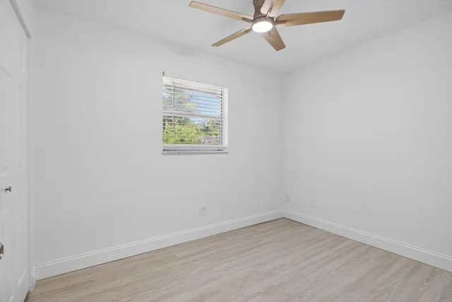 an empty room with a window and a fan