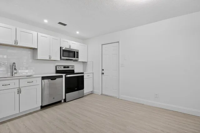 a kitchen with sink a microwave and cabinets