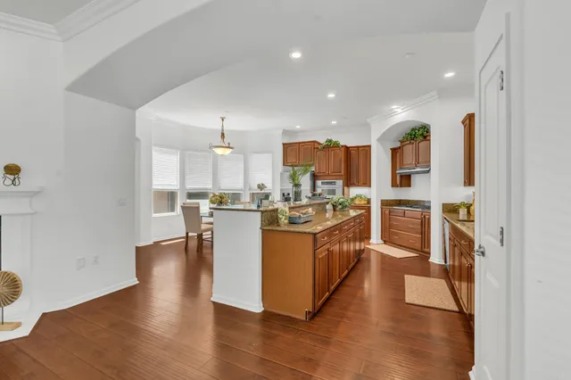 a living room with furniture kitchen view and a wooden floor