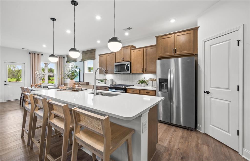 808 Tupelo Way Villa Rica, GA 30180 - Photo 12 of 48 a kitchen with kitchen island a refrigerator a sink a stove and chairs