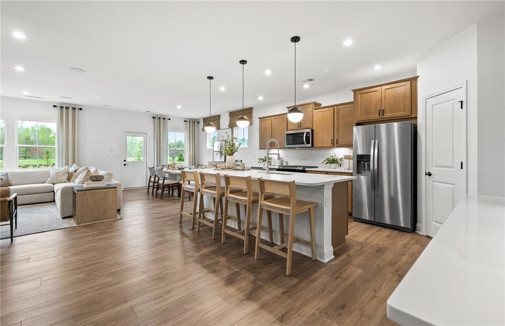 808 Tupelo Way Villa Rica, GA 30180 - Photo 10 of 48 a kitchen with stainless steel appliances kitchen island granite countertop a stove a refrigerator a kitchen island a dining table and chairs with wooden floor