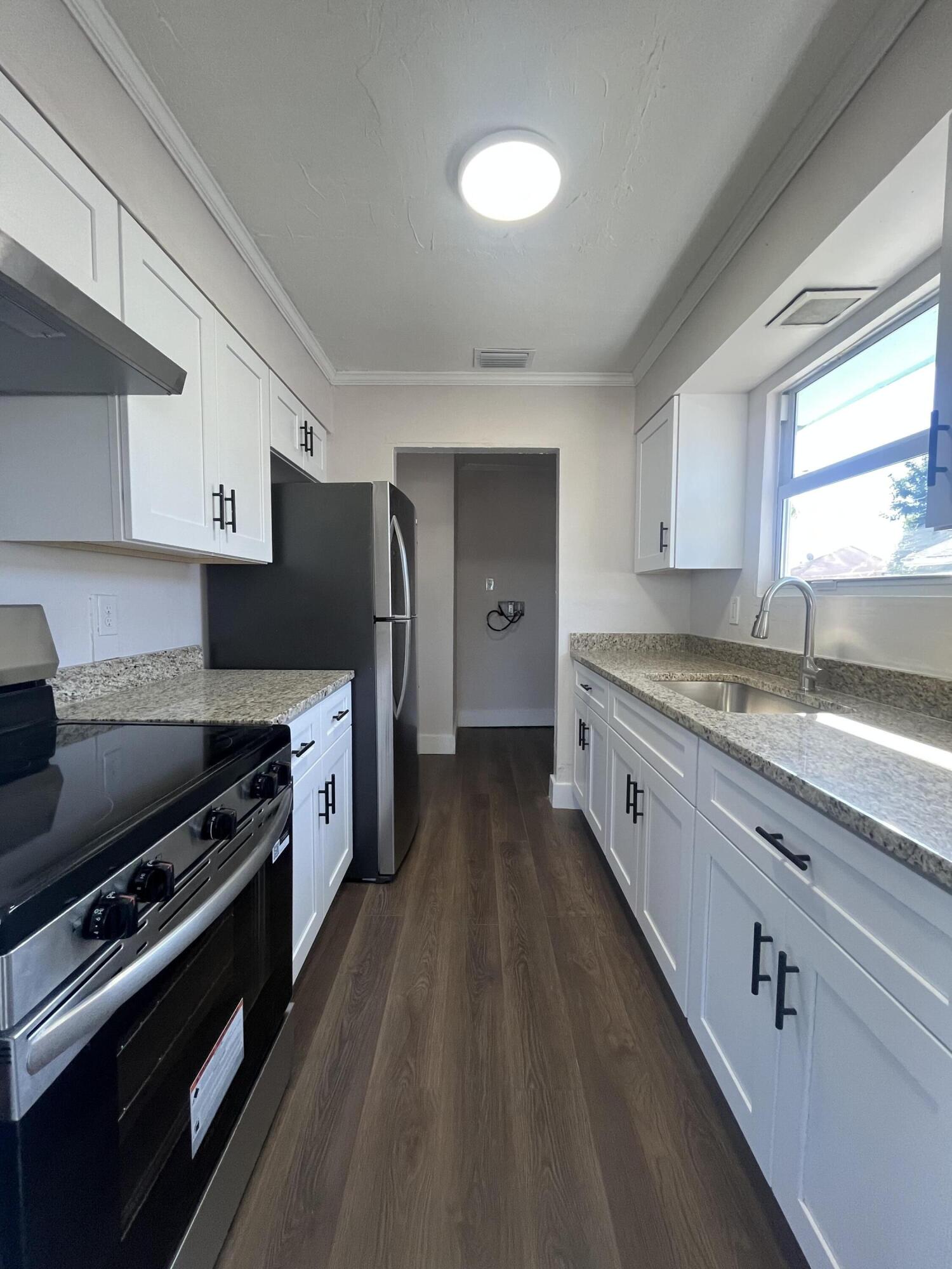 1457 West 32nd Street Riviera Beach, FL 33404 - Photo 5 of 5 a kitchen with granite countertop a stove a sink dishwasher and a refrigerator