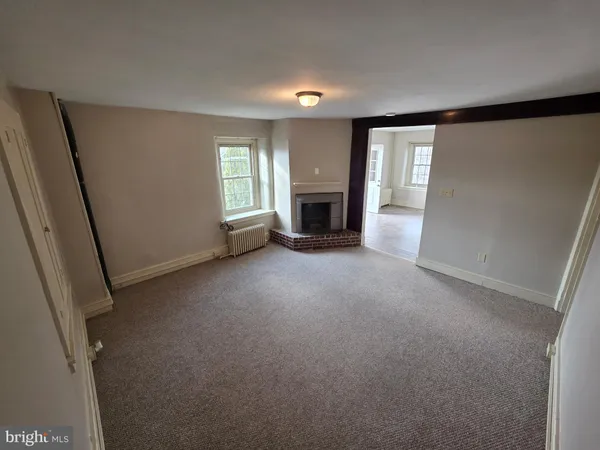 an empty room with windows and fireplace