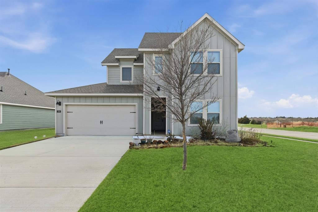 View of front of property with board and batten siding, roof with shingles, a front lawn, and driveway