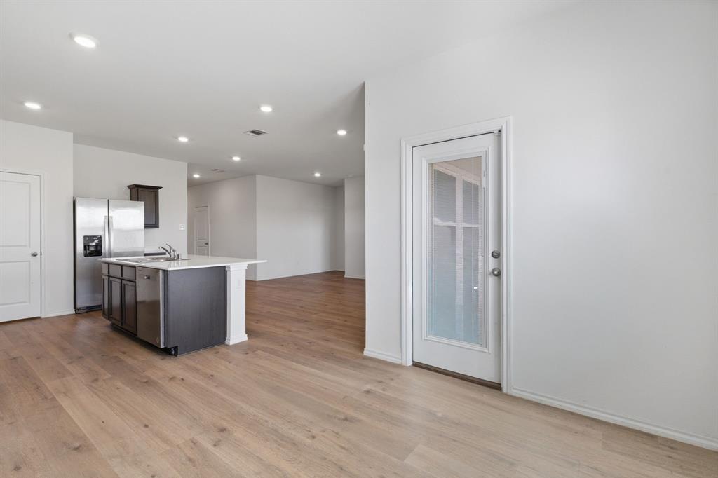 709 Primrose Lane Pilot Point, TX 76258 - Photo 34 of 35 Kitchen with stainless steel appliances, a kitchen island with sink, open floor plan, light wood-style floors, and recessed lighting