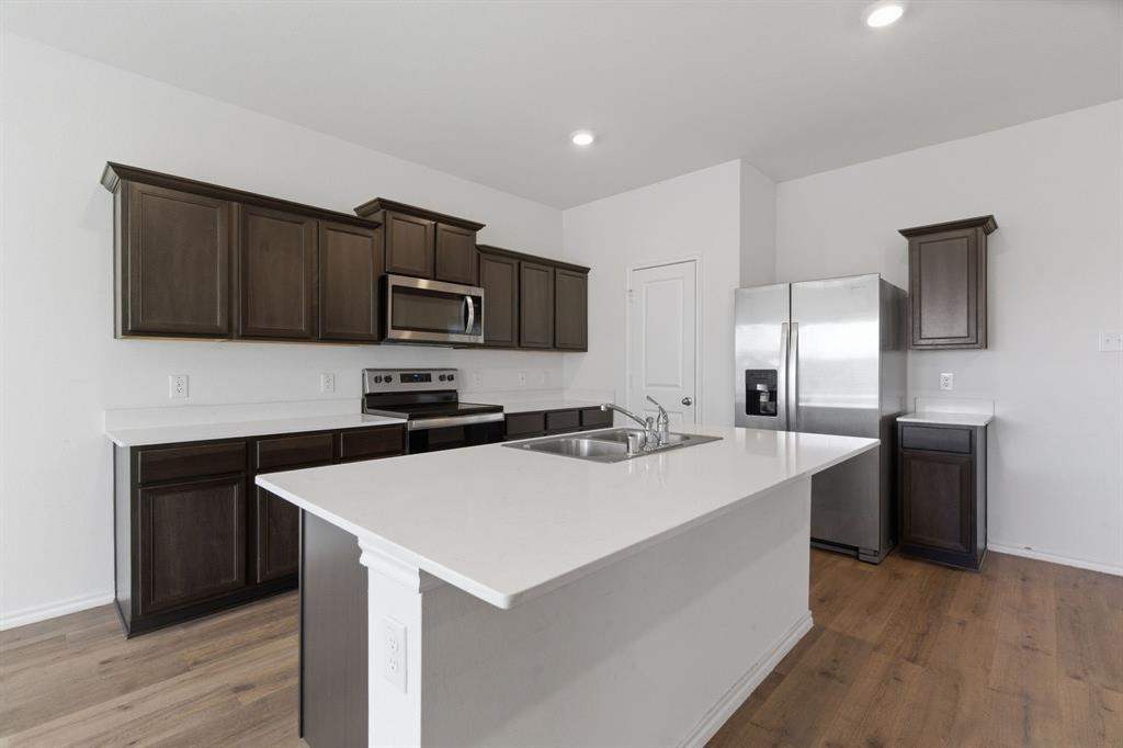709 Primrose Lane Pilot Point, TX 76258 - Photo 6 of 35 Kitchen with stainless steel appliances, dark wood finish cabinets, an island with sink, dark wood-style flooring, and recessed lighting