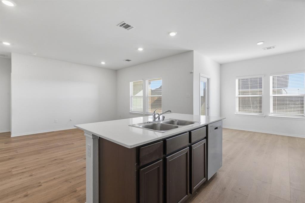 709 Primrose Lane Pilot Point, TX 76258 - Photo 8 of 35 Kitchen with dark wood finish cabinets, a center island with sink, light wood-style flooring, stainless steel dishwasher, and recessed lighting