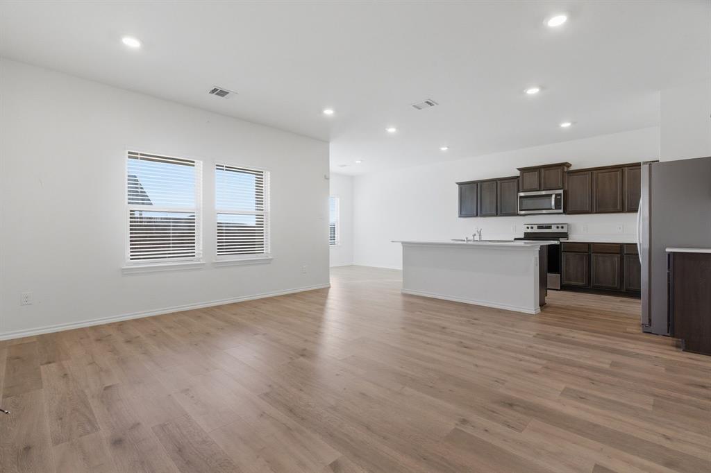 709 Primrose Lane Pilot Point, TX 76258 - Photo 33 of 35 Kitchen featuring open floor plan, stainless steel appliances, light countertops, a center island with sink, and dark wood finish cabinetry