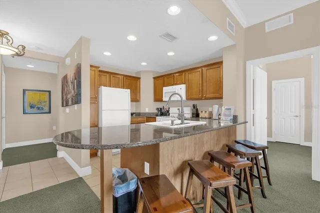 a kitchen with kitchen island granite countertop lots of white cabinets appliances and a dining table