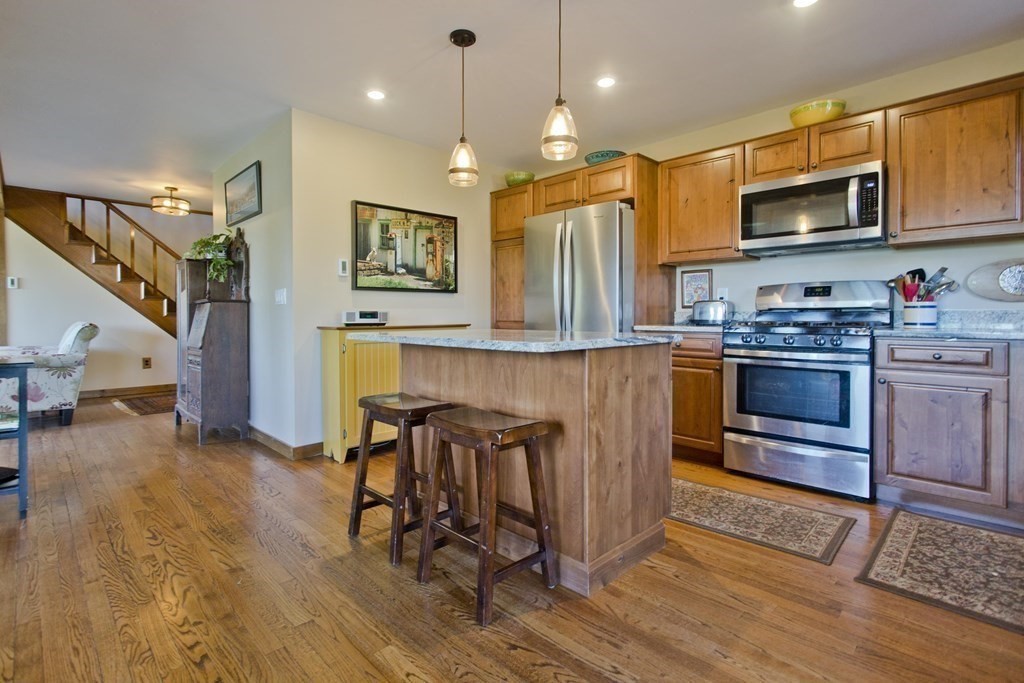 135 George Lamb Road Leyden, MA 01337 - Photo 8 of 42 a kitchen with stainless steel appliances granite countertop a stove top oven a sink dishwasher a dining table and chairs with wooden floor