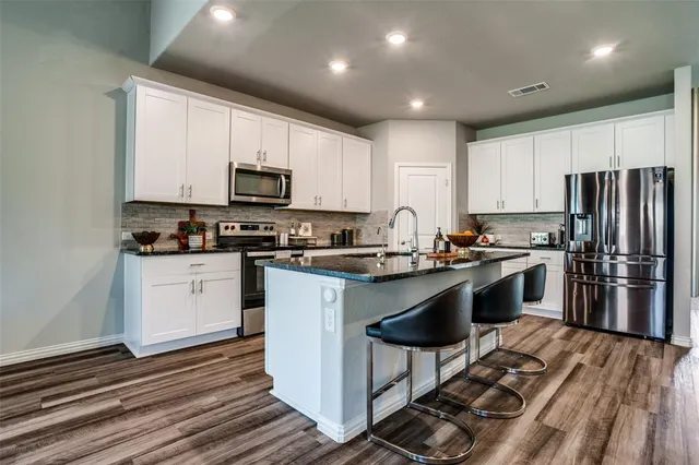 a kitchen with granite countertop a refrigerator stove top oven and sink