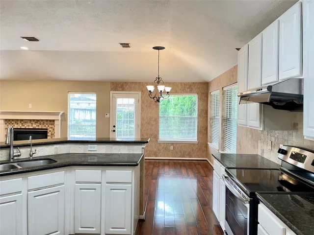 a kitchen with stainless steel appliances granite countertop a sink a stove and a wooden floors