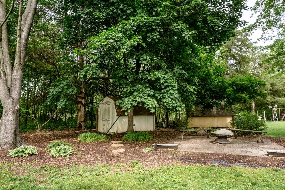 87 Bluestone Drive Weyers Cave, VA 24486 - Photo 34 of 37 a view of a backyard with large trees and a small barn