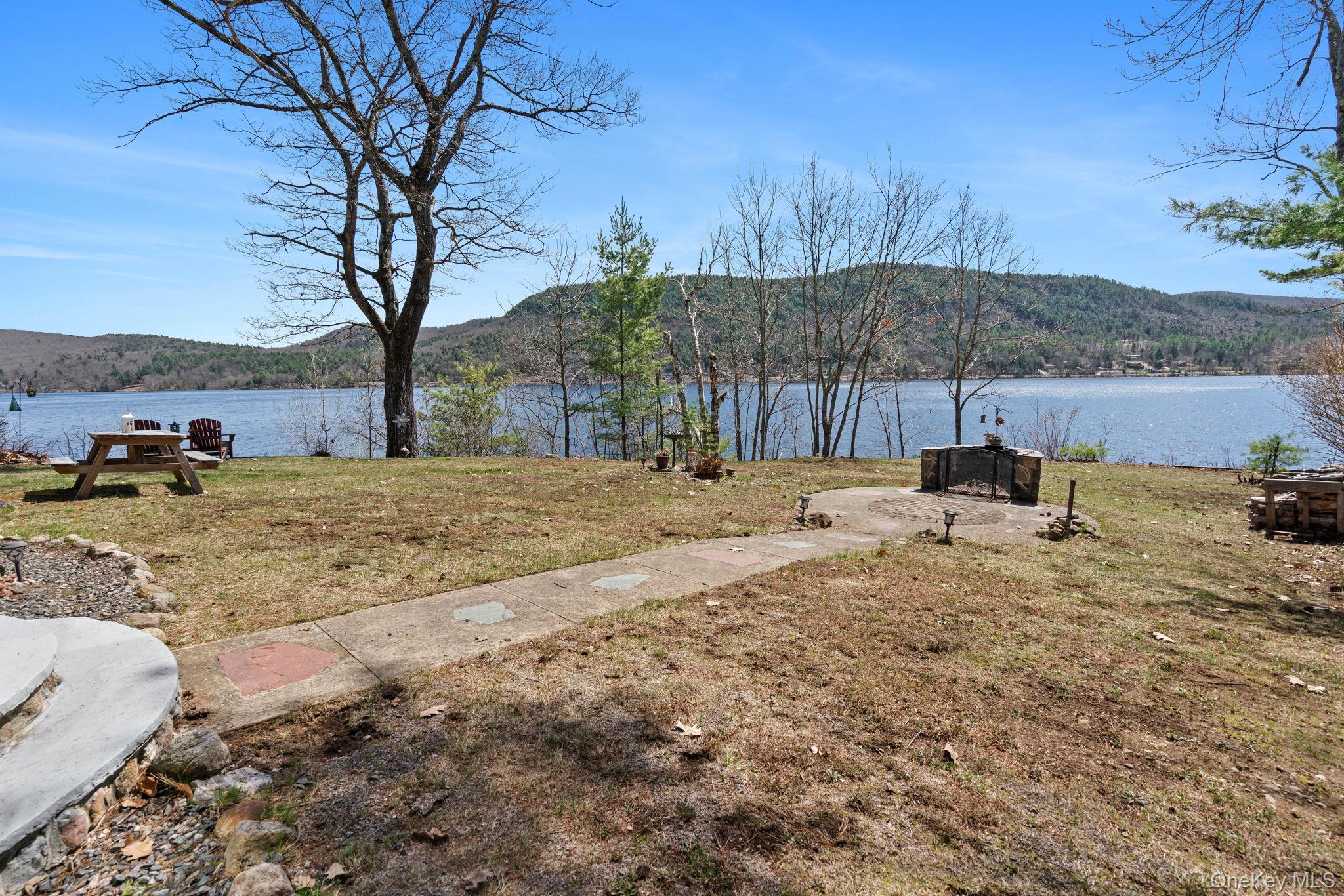 866 North Shore Road Hadley, NY 12835 - Photo 46 of 50 Expansive waterfront property featuring a stone fire pit area, paved walkway, and a spacious lawn