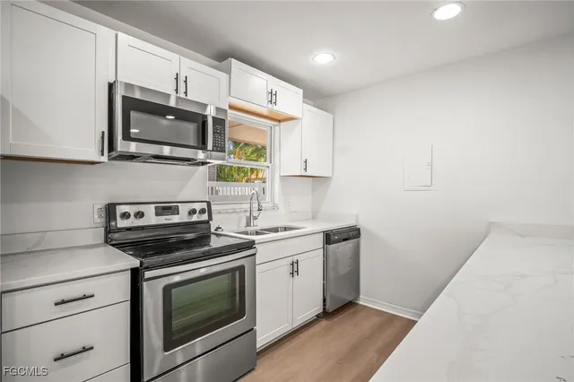 a view of a kitchen with stainless steel appliances a sink a stove a microwave a center island and a window