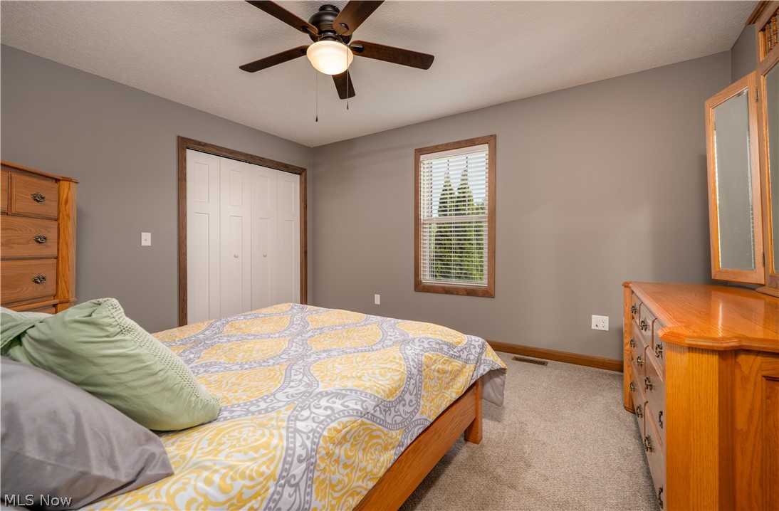 3515 Eastport Road Southeast Dennison, OH 44621 - Photo 38 of 41 Carpeted room featuring a ceiling fan with integrated lighting, a window with horizontal blinds, and a built-in bi-fold closet with wood trim