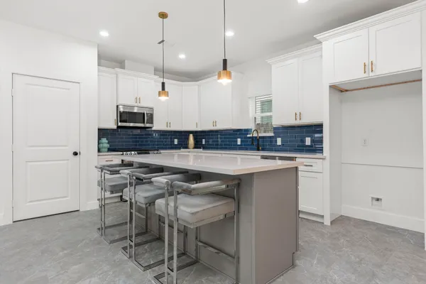 a kitchen with kitchen island granite countertop a sink a counter space appliances and cabinets