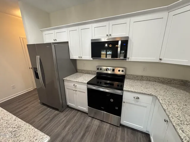 a kitchen with a refrigerator stove and white cabinets