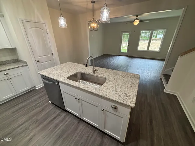 a kitchen with a sink dishwasher a stove a dining table and chairs with wooden floor