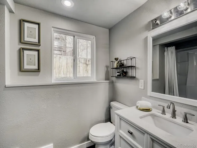 a bathroom with a granite countertop toilet sink and mirror